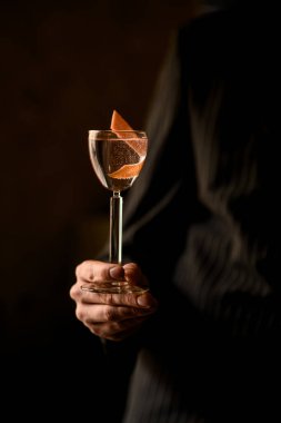 Erkek barmenler ellerinde votka dolu bir bardak sapıyla siyah arka planda bükülmüş bir parça kabukla el ele tutuşuyorlar.