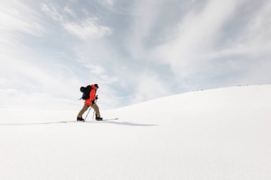 Kayakçının alttaki görüntüsü kayakların üzerinde yumuşak bir yamaca tırmanırken güzel bulutsuz mavi bir gökyüzünün arka planına doğru.