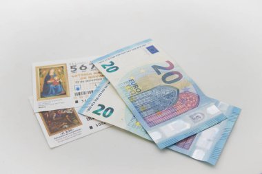 Tarafsız beyaz bir arka planda iki 20 'lik banknotun yanında ulusal piyango biletlerinin görüntüsü.