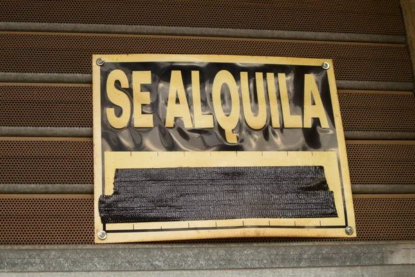 Close-up of a sign attached to a shop shutter indicating that the premises are for rent written in Spanish (\