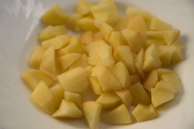 Beyaz bir tabakta taze soyulmuş ve doğranmış patatesler. Patates kızartması yapmaya hazır.