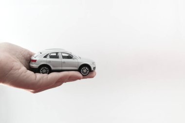 Closeup of a miniature modern car that is held by a hand on white background with copy space