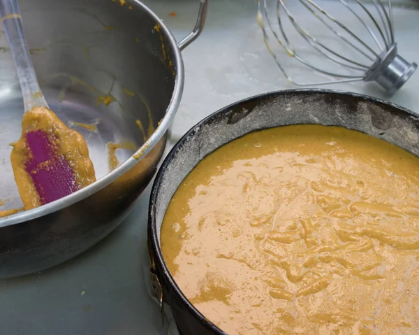 Finishing the preparation of a carrot cake, in the foreground is a bowl with the raw dough ready to bake
