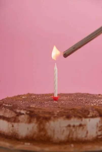 Birthday or anniversary cake with a candle being lit with a lighter on a cake decorated with chocolate. Image with copy space