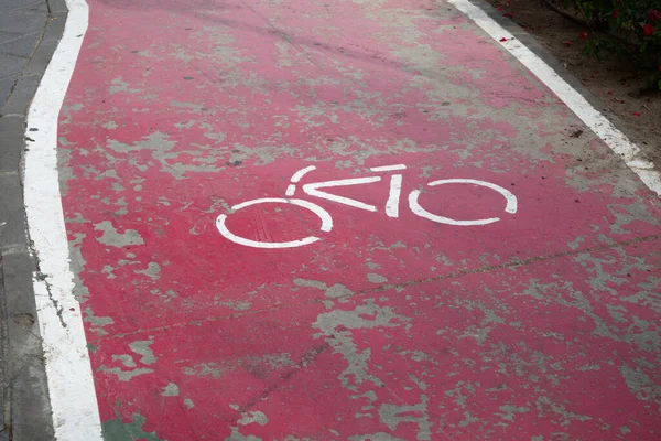 Red bike lane and paint worn by time in which the icon of a bicycle has been painted on the asphalt indicating that two-wheeled vehicles such as bikes and skateboards have preference