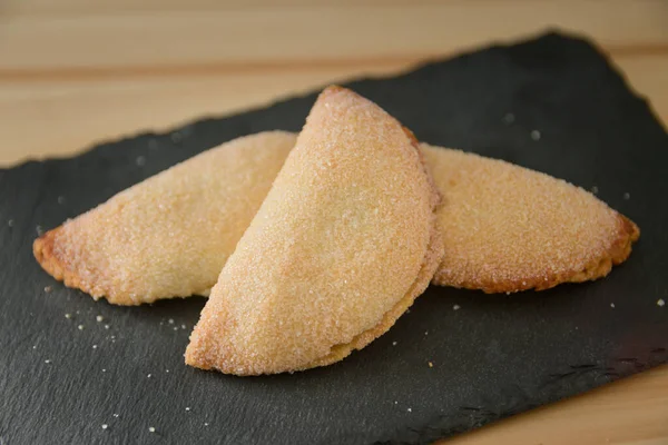 Still life of some sweet potato cakes, a traditional sweet during Christmas in Valencia (Spain), on a black slate table with copy space