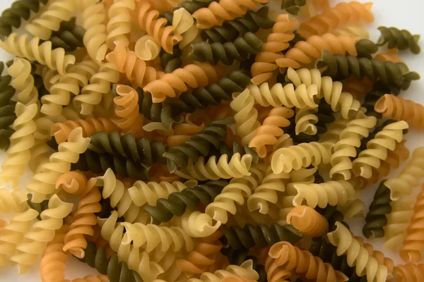 View from above of a plate of fusilli, Italian short pasta, shaped like a helix of various colors green, yellow, orange