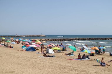 Şemsiyeleri ve havlularıyla güneşlenen insanlarla dolu bir plajın bulanık görüntüsü. Boşluğu kopyala