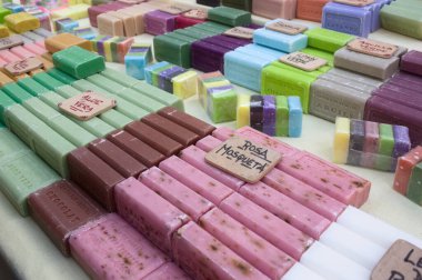 Renkleri ve kokuları özelliklerini belirleyen çok çeşitli doğal sabunların satışa sunulduğu bir market tezgahının yakın çekimi
