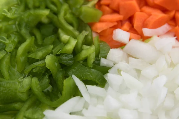 Closeup from above of a plate of chopped and chopped vegetables with green pepper, carrot, white onion