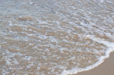 Küçük bir dalganın temiz bir kumsala banyo yapmadan ulaşması.