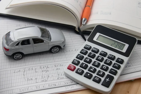 Still life illustrating the worry caused by daily life payments, a calculator next to a car and notes on tax costs