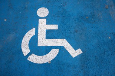 Mavi arka plandaki engelliler için park yerindeki beyaz trafik işaretinin ayrıntıları