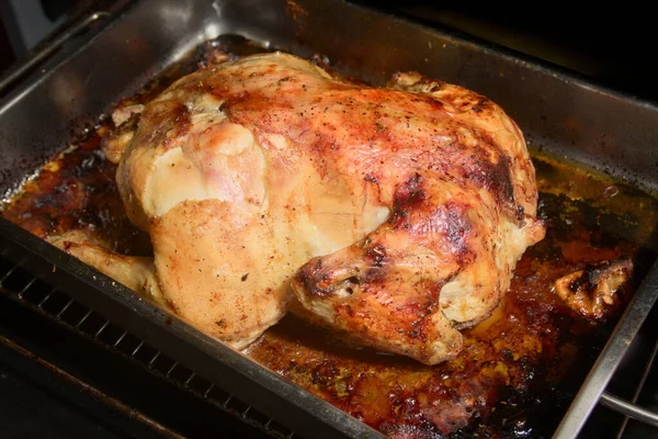 Close-up of a whole chicken that has been roasted in a home oven tray, resulting in crispy, golden skin ready to taste