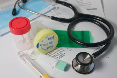 Dışkı, idrar testi, kan testi sonuçları steteskop. Maske gibi tıbbi malzemelerle dolu bir doktor masası.