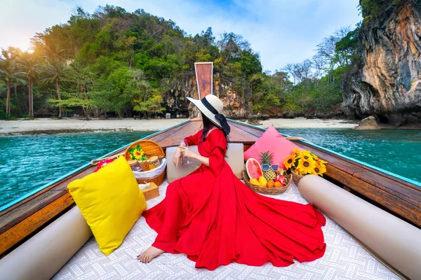 Beautiful girl in red dress on longtail boat at Koh Lao Lading island, Thailand.