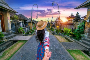 Erkeğin elini tutan ve onu Penglipuran köyüne götüren kadın turistler Bali, Endonezya 'daki geleneksel bir Bali köyüdür..