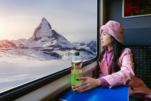列車に座っている間マッターホルン山を楽しむウィンドウを見渡す観光客 スイスのツェルマット ストック画像
