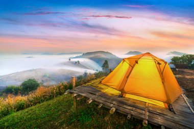 Kamp çadırı ve altın güneş ışığı Tayland 'ın dağlarındaki sisi delip geçiyor..