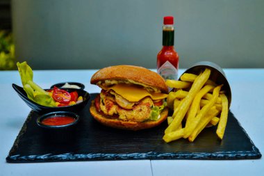 Tavuk burger ve peynir. Siyah mermerde salata ve meşrubat