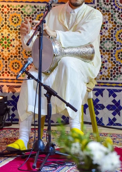 Music shot of man playing   arabic darbuka at the same time on an alternative house studio background. Having fun experimenting with exotic instruments at home.