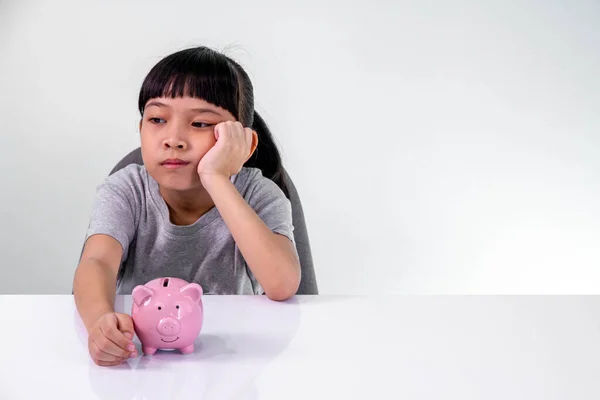 Beautiful little girl is very sad because she didn\'t save enough money to buy something.Sad little girl with piggy bank