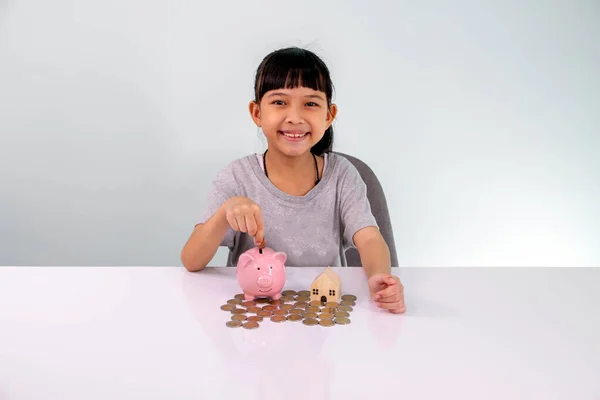 Little Asian girl saving money in a piggy bank, learning about saving, Kid save money for future education. Money, finances