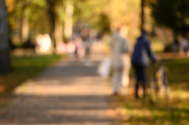 Şehir parkında yürüyen insanlar. Güzel bir sonbahar sezonu. Bulanık arkaplan