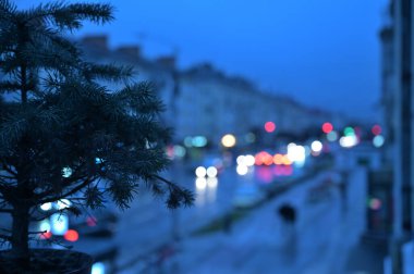 Pencere kenarında noel ağacı ve şehir ışıkları arka planda bulanık