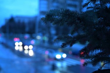 Pencere kenarında noel ağacı ve şehir ışıkları arka planda bulanık