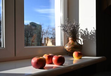 Pencere kenarındaki vazoda elmalar ve lavantalar