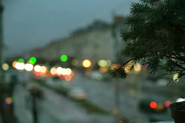 窓のクリスマスツリーと夜の街のライトがぼやけた背景 — ストック写真