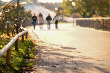 İnsanlar güneşli bir günde parkta yürürler.