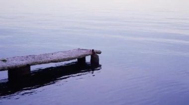 Reflections on the sea surface at evening sunset. Dock and sea. Tranquility.