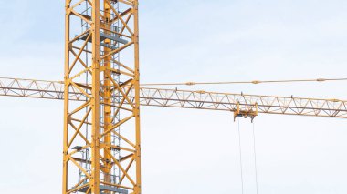 Low-angle view of a construction crane at work on a building site. High qual
