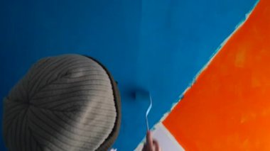 Boya evi. Orta yaşlı bir kadın boya fırçasıyla ev boyuyor..