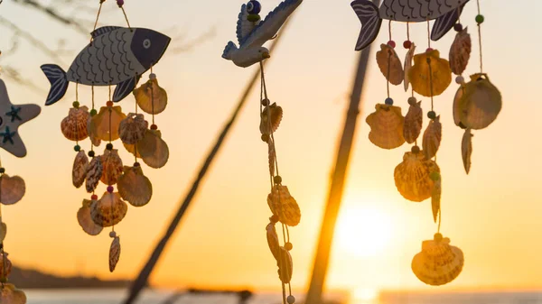 Wind bell made of sea shells. Wind chime made of sea shells. Decorative summer house ornaments. Summer vacation concept during sunset sky