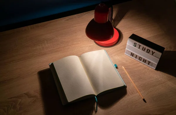 Study concept background. Notepad with blank pages and desk lamp on wooden table high angle view. Study time concept. Selective focus on notebook