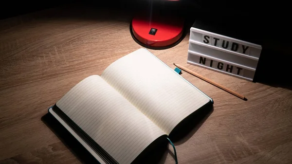 Study concept background. Notepad with blank pages and desk lamp on wooden table high angle view. Study time concept. Selective focus on notebook