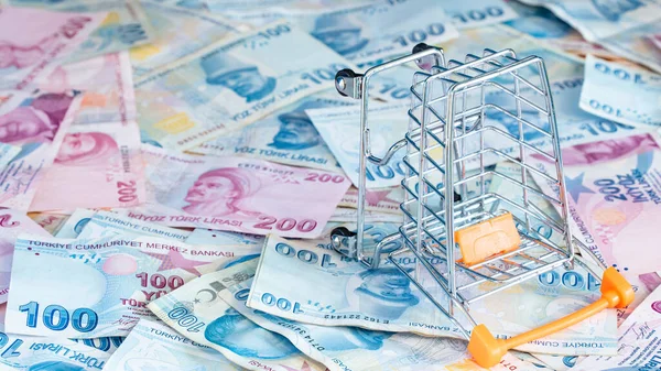 Cost of living concept. Empty cart on a stack of Turkish liras. Inflation rising in Turkey. Economic crisis. Rising costs in daily life