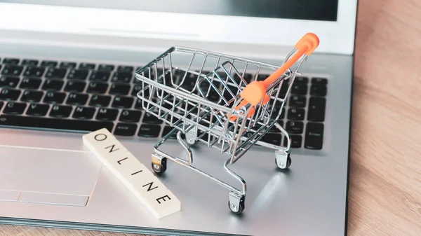 stock image Online shopping concept. Shopping cart or trolley and laptop on wooden table