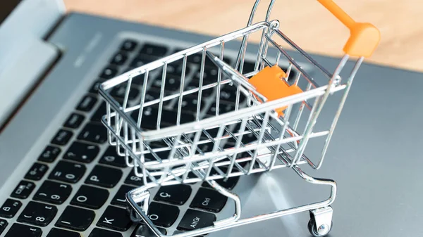 stock image Online shopping concept. Shopping cart or trolley and laptop on wooden table