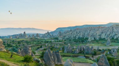 Kapadokya hindisi. Kapadokya 'da güneş doğarken bacaların üzerinde uçan sıcak hava balonları. Türkiye 'ye git. Türkiye 'nin turistik simgeleri. Seçici odak dahil