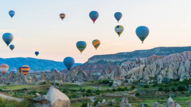 Kapadokya hindisi. Kapadokya 'da güneş doğarken bacaların üzerinde uçan sıcak hava balonları. Türkiye 'ye git. Türkiye 'nin turistik simgeleri. Seçici odak dahil