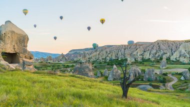 Kapadokya hindisi. Kapadokya 'da güneş doğarken bacaların üzerinde uçan sıcak hava balonları. Türkiye 'ye git. Türkiye 'nin turistik simgeleri. Seçici odak dahil
