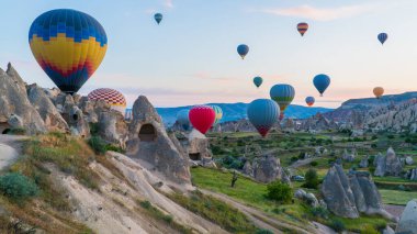 Kapadokya hindisi. Kapadokya 'da güneş doğarken bacaların üzerinde uçan sıcak hava balonları. Türkiye 'ye git. Türkiye 'nin turistik simgeleri. Seçici odak dahil