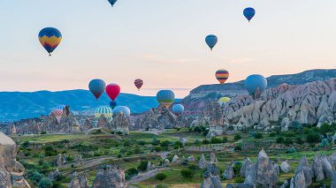 Kapadokya hindisi. Kapadokya 'da güneş doğarken bacaların üzerinde uçan sıcak hava balonları. Türkiye 'ye git. Türkiye 'nin turistik simgeleri. Seçici odak dahil