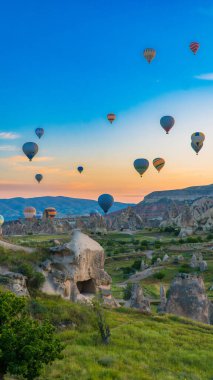 Kapadokya hindisi. Kapadokya 'da güneş doğarken bacaların üzerinde uçan sıcak hava balonları. Türkiye 'ye git. Türkiye 'nin turistik simgeleri. Seçici odak dahil