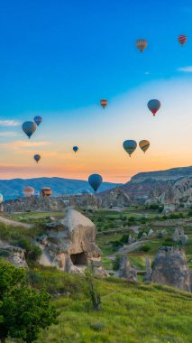 Kapadokya hindisi. Kapadokya 'da güneş doğarken bacaların üzerinde uçan sıcak hava balonları. Türkiye 'ye git. Türkiye 'nin turistik simgeleri. Seçici odak dahil