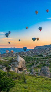 Kapadokya hindisi. Kapadokya 'da güneş doğarken bacaların üzerinde uçan sıcak hava balonları. Türkiye 'ye git. Türkiye 'nin turistik simgeleri. Seçici odak dahil